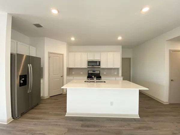 a view of a kitchen with a sink refrigerator and wooden floor