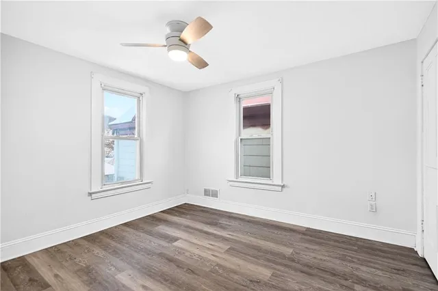 an empty room with wooden floor and ceiling fan