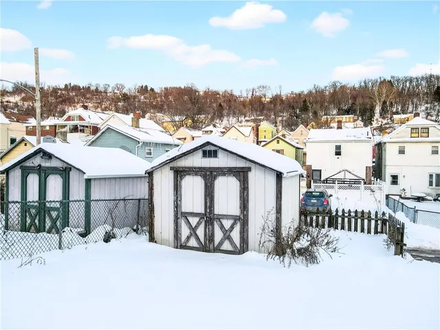 a view of a white house with wooden fence