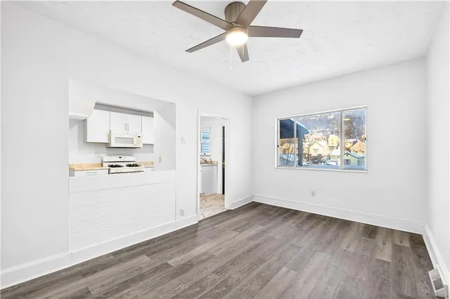 a view of an empty room with window and wooden floor