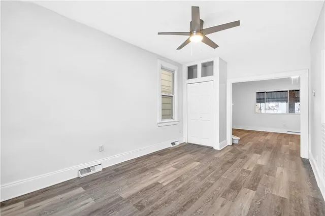 an empty room with wooden floor and windows