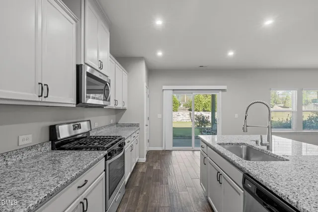 a kitchen with stainless steel appliances granite countertop a refrigerator sink and white cabinets