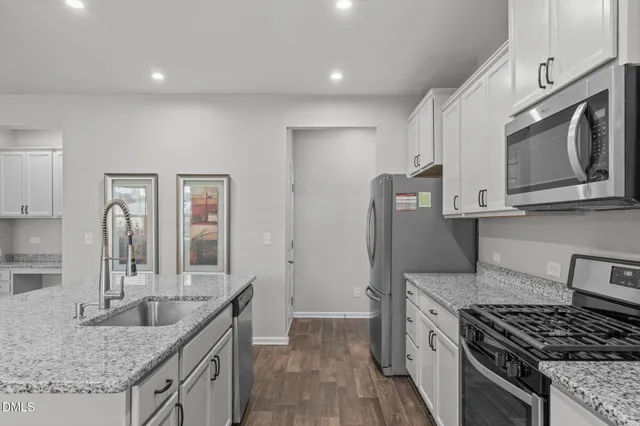 a kitchen with stainless steel appliances granite countertop a stove a refrigerator and a refrigerator with wooden floors