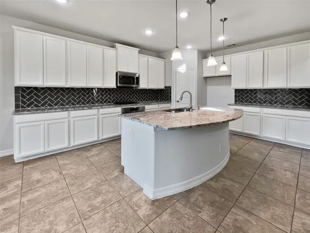 a kitchen with kitchen island granite countertop a sink a stove a counter top space and cabinets