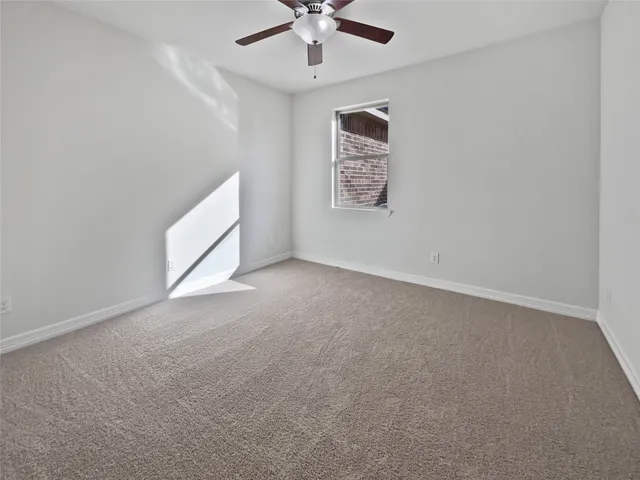 an empty room with a ceiling fan and a window