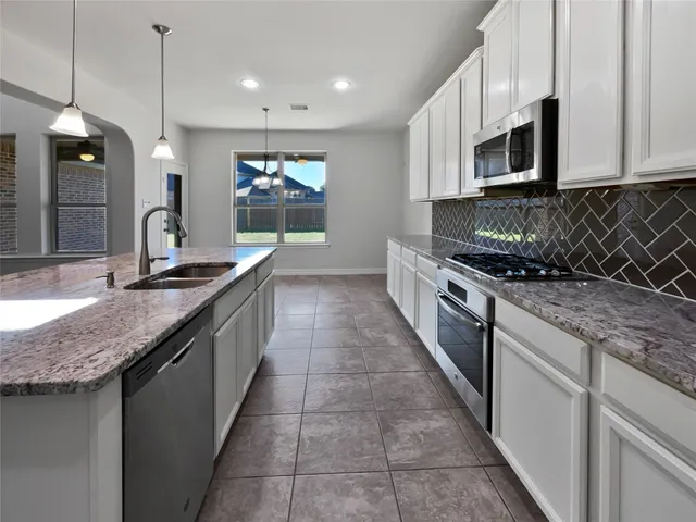 a large kitchen with granite countertop a sink and a stove