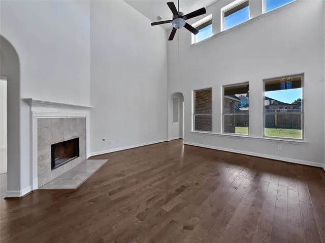 a view of an empty room with wooden floor fireplace and a window