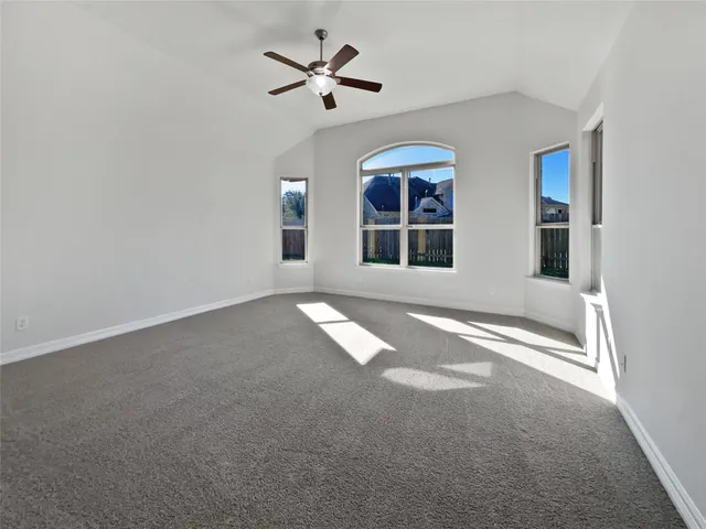 an empty room with windows and ceiling fan