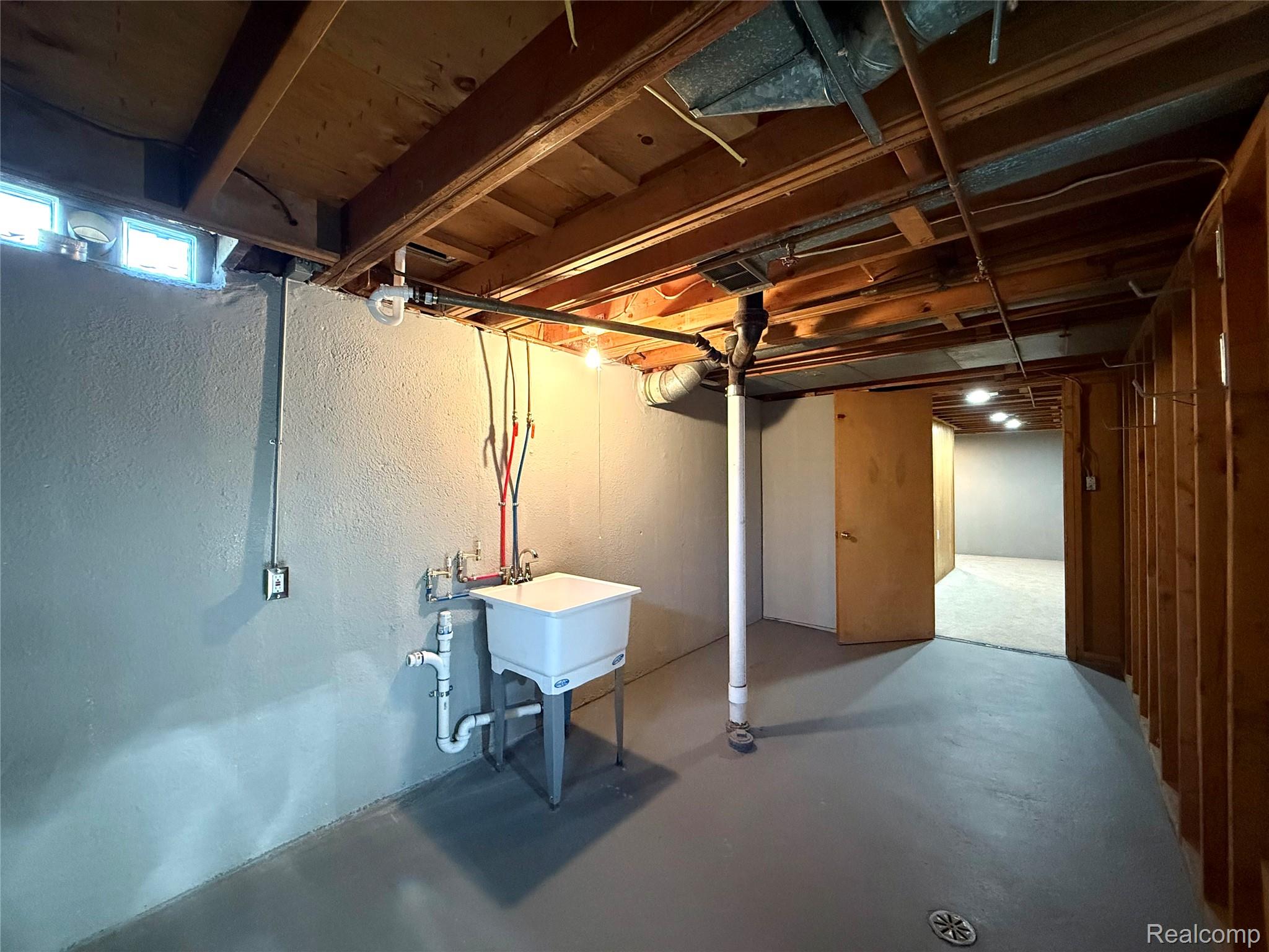 39909 Lynn Street Canton, MI 48187 - Photo 35 of 45 Basement utility area featuring a wall-mounted laundry sink, exposed wood joists, overhead lighting, and a concrete floor