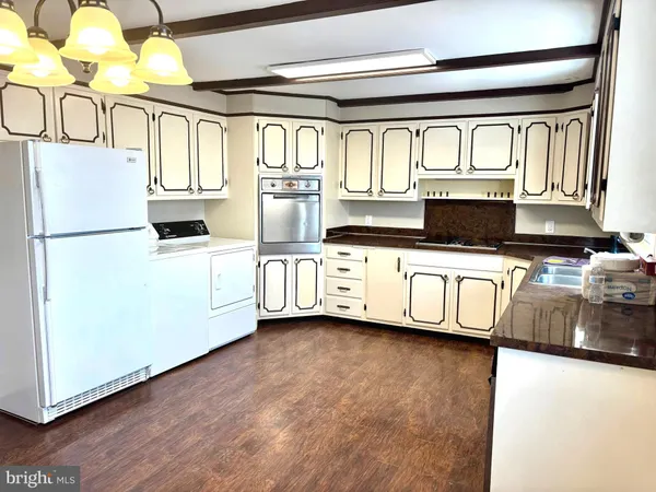 a kitchen with stainless steel appliances granite countertop a stove a sink and a refrigerator with wooden floors