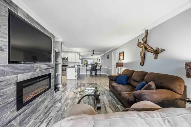 a living room with stainless steel appliances furniture a fireplace and wooden floor