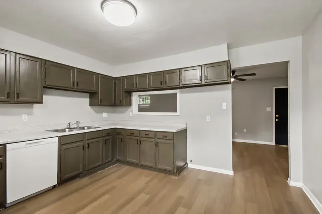 a kitchen with stainless steel appliances granite countertop a sink and cabinets with wooden floors
