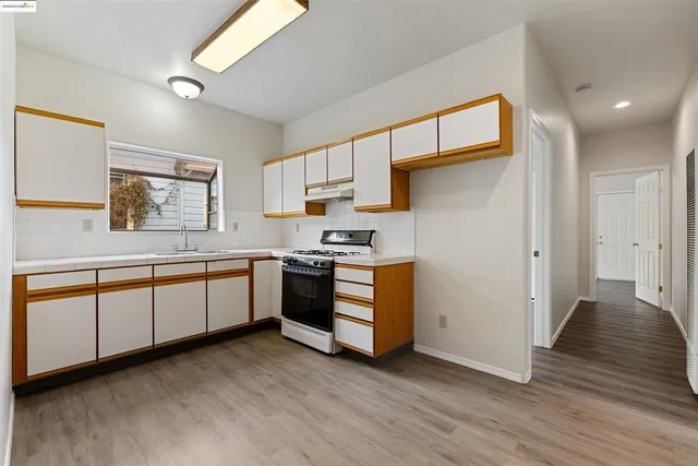 a kitchen with stainless steel appliances granite countertop a stove a sink and a refrigerator with wooden floors