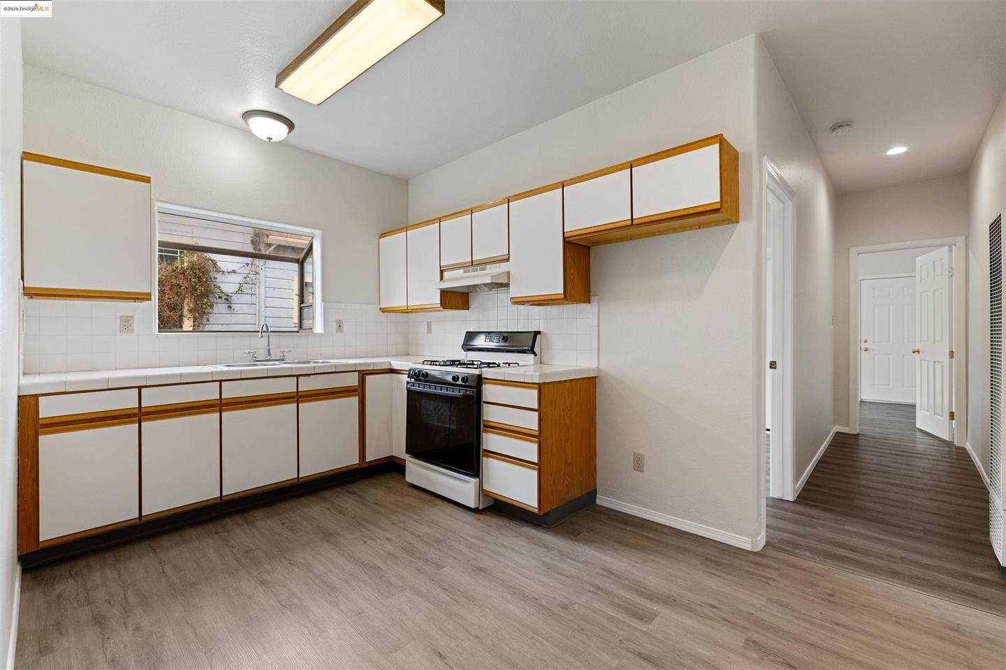 1619 Fairview Street, Unit 2 Berkeley, CA 94703 - Photo 5 of 6 a kitchen with stainless steel appliances granite countertop a stove a sink and a refrigerator with wooden floors