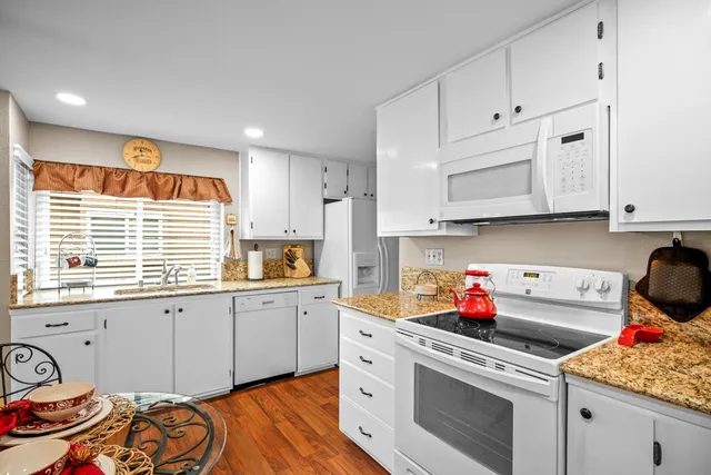 a kitchen with granite countertop white cabinets and white appliances