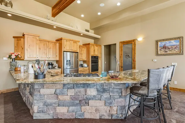 a dining hall with stainless steel appliances kitchen island granite countertop a table and chairs