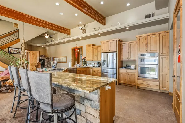 a dining hall with stainless steel appliances kitchen island granite countertop a table and chairs