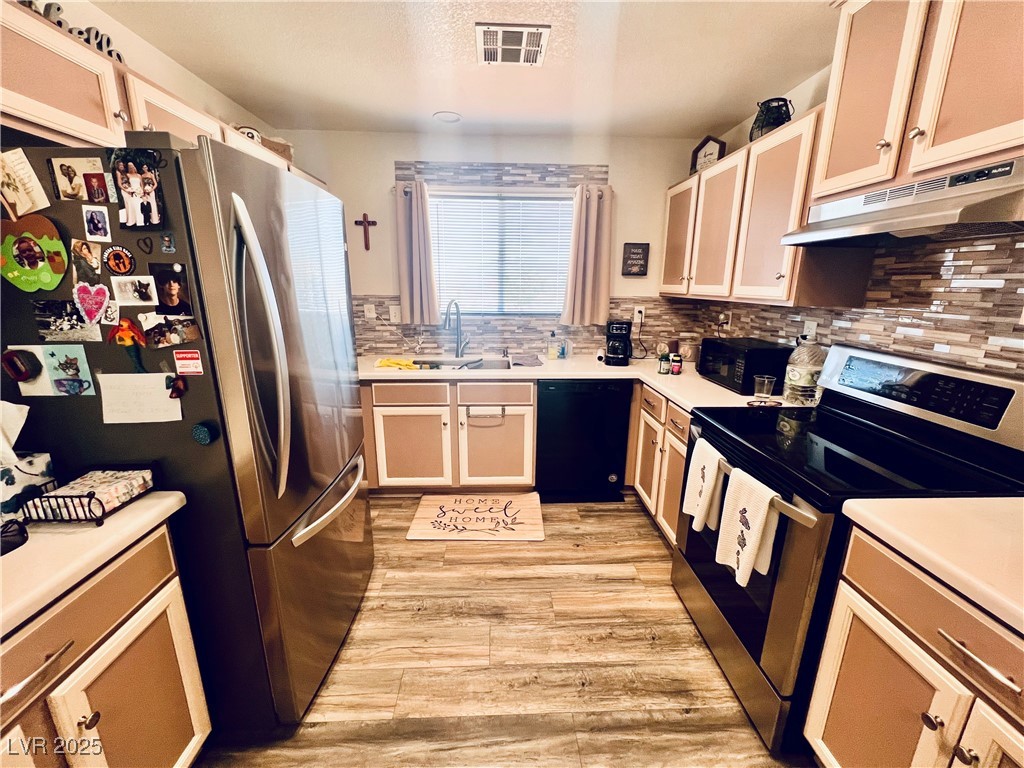 2970 Rio Rico Drive Pahrump, NV 89048 - Photo 19 of 53 Kitchen featuring stainless steel appliances, light countertops, under cabinet range hood, light wood-style flooring, and tasteful backsplash