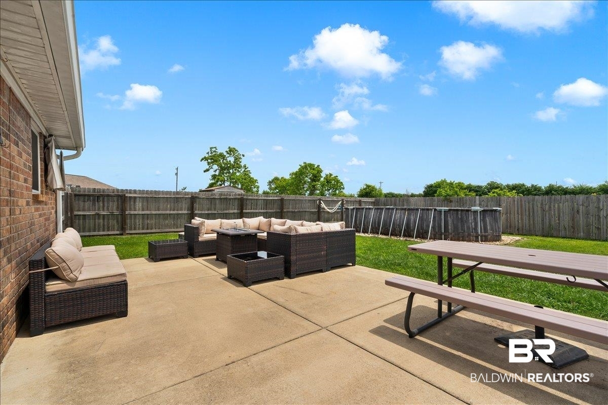 8952 Sherman Road Foley, AL 36535 - Photo 40 of 41 Spacious concrete patio extending from the brick exterior, featuring a private fenced yard with green lawn