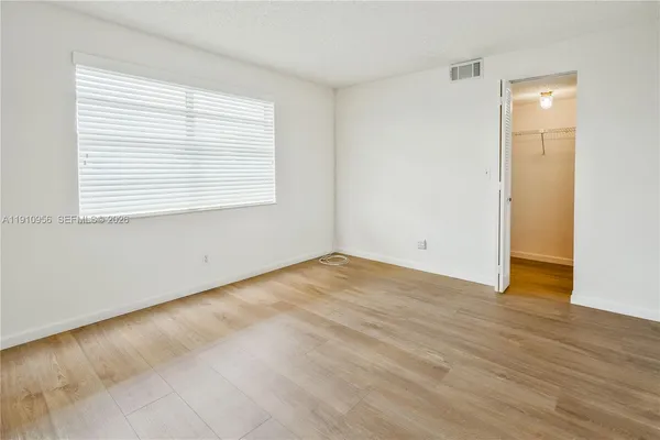 an empty room with wooden floor and windows