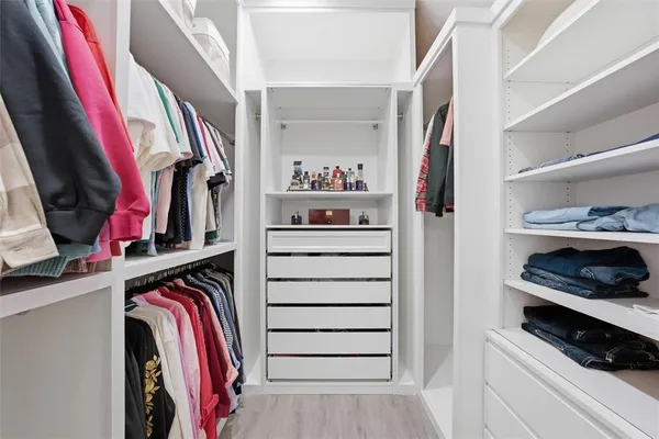 a view of walk in closet with clothes and shoes