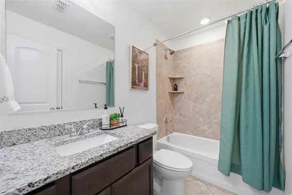 a bathroom with a granite countertop sink a toilet and shower