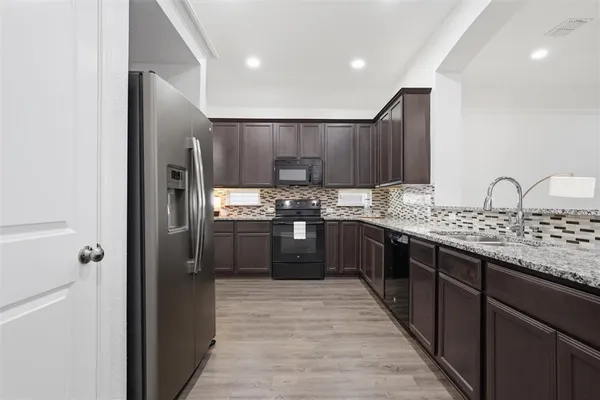a large kitchen with stainless steel appliances kitchen island granite countertop a refrigerator and a sink