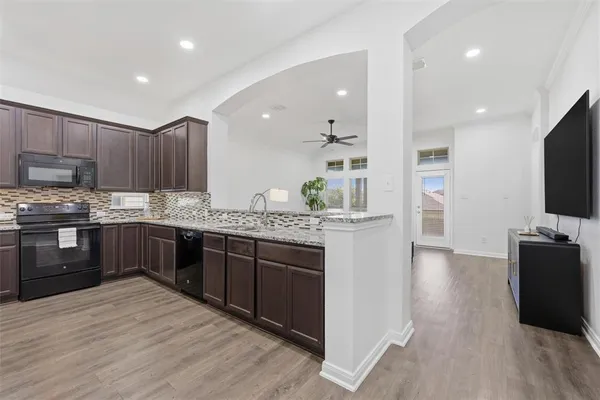a kitchen with stainless steel appliances kitchen island granite countertop a stove refrigerator and cabinets