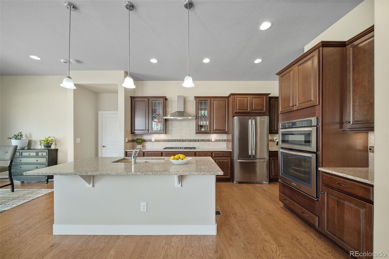 17670 West 94th Drive Arvada, CO 80007 - Photo 13 of 49 a large kitchen with kitchen island a large counter top stainless steel appliances and cabinets