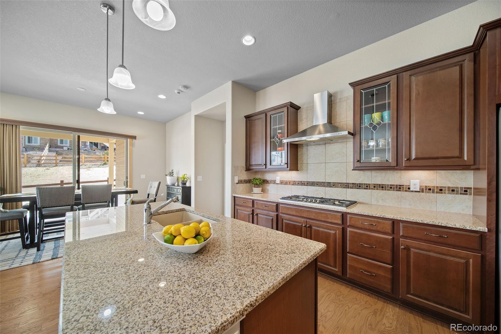17670 West 94th Drive Arvada, CO 80007 - Photo 15 of 49 a kitchen with stainless steel appliances granite countertop wooden cabinets a stove a sink a dining table and chairs
