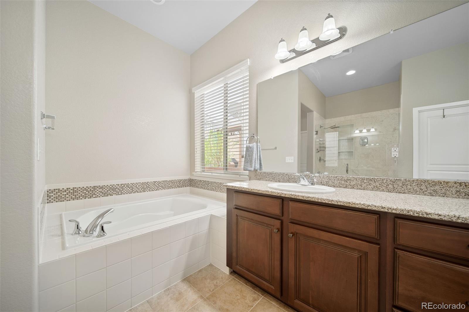 17670 West 94th Drive Arvada, CO 80007 - Photo 25 of 49 a bathroom with a granite countertop bathtub a double vanity sink and mirror