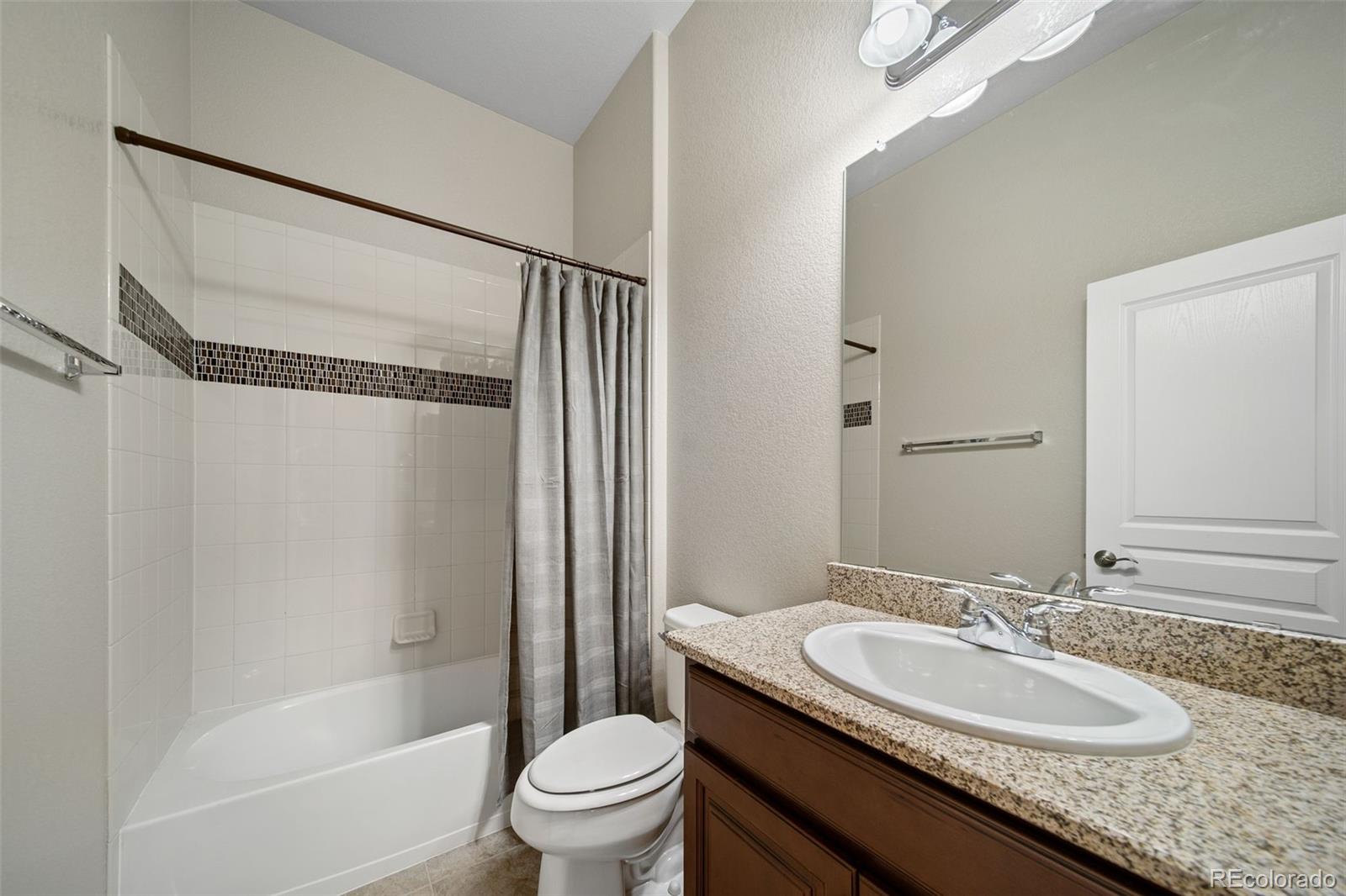 17670 West 94th Drive Arvada, CO 80007 - Photo 29 of 49 a bathroom with a granite countertop sink toilet mirror and a bathtub