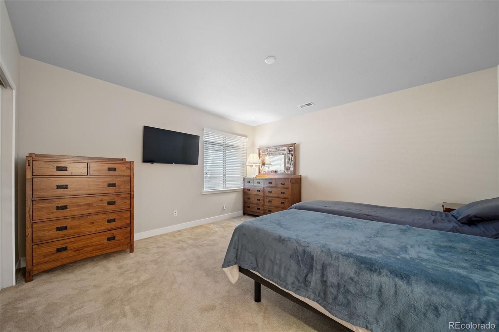 17670 West 94th Drive Arvada, CO 80007 - Photo 37 of 49 a spacious bedroom with a bed and a flat screen tv