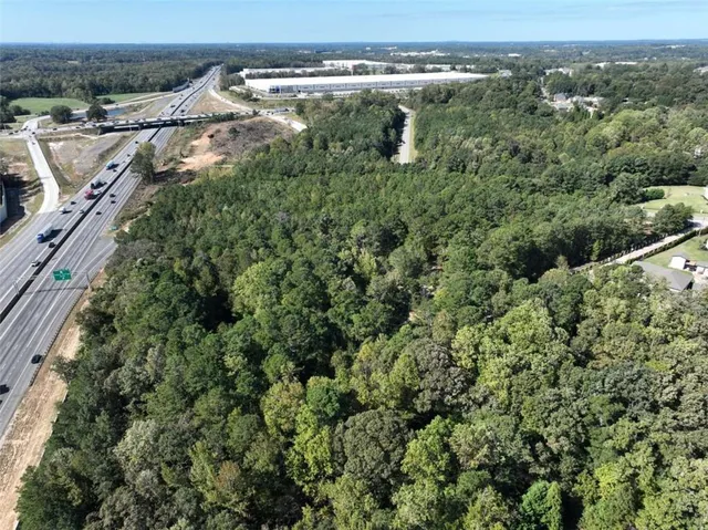 an aerial view of a residential houses with outdoor space and trees