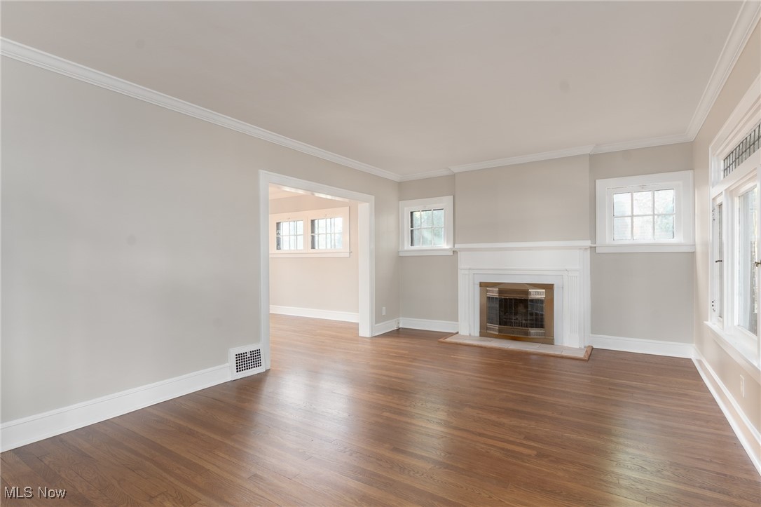 3459 Helen Road Shaker Heights, OH 44122 - Photo 4 of 29 Unfurnished living room with baseboards, crown molding, wood finished floors, and a glass covered fireplace