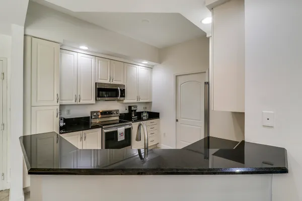 a kitchen with stainless steel appliances granite countertop a sink a stove and a refrigerator