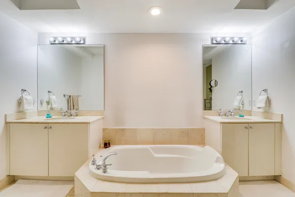 a bathroom with a tub a sink and mirror