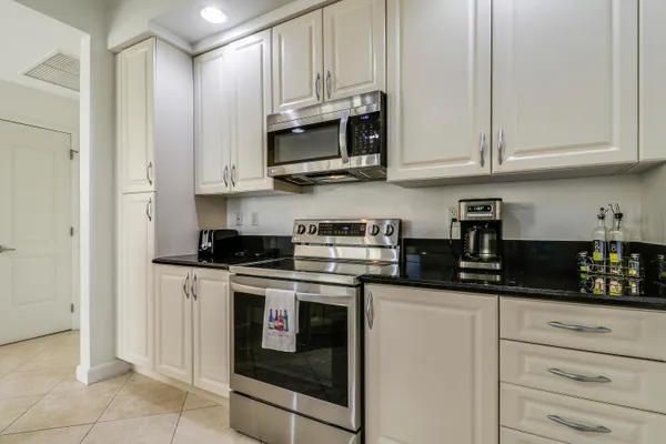 a kitchen with stainless steel appliances granite countertop white cabinets and a stove a oven with white countertops