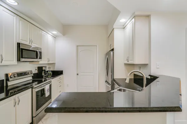 a kitchen with granite countertop a sink stove and microwave