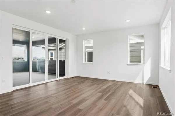an empty room with wooden floor and windows