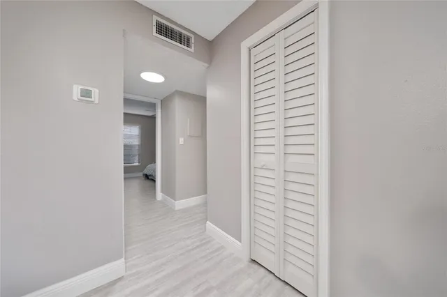 a view of a hallway with wooden floor and closet