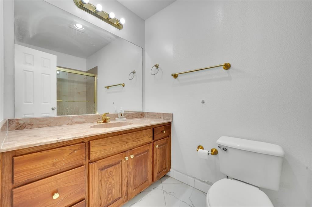 4610 Bucknell Drive Garland, TX 75042 - Photo 16 of 25 a bathroom with a granite countertop sink a toilet and a mirror