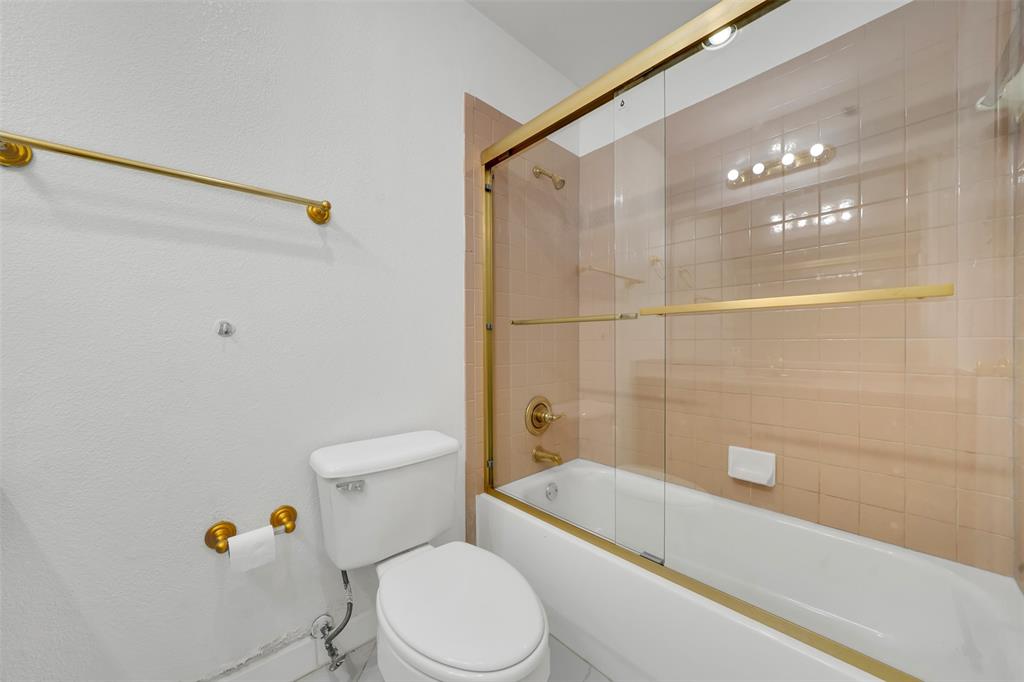 4610 Bucknell Drive Garland, TX 75042 - Photo 17 of 25 a white toilet sitting next to a bathroom sink and a shower