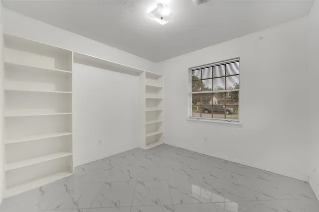 an empty room with windows and fan