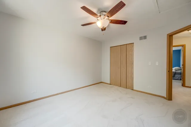 an empty room with closet and a ceiling fan