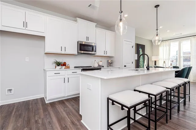 a kitchen with stainless steel appliances a white table chairs refrigerator and microwave