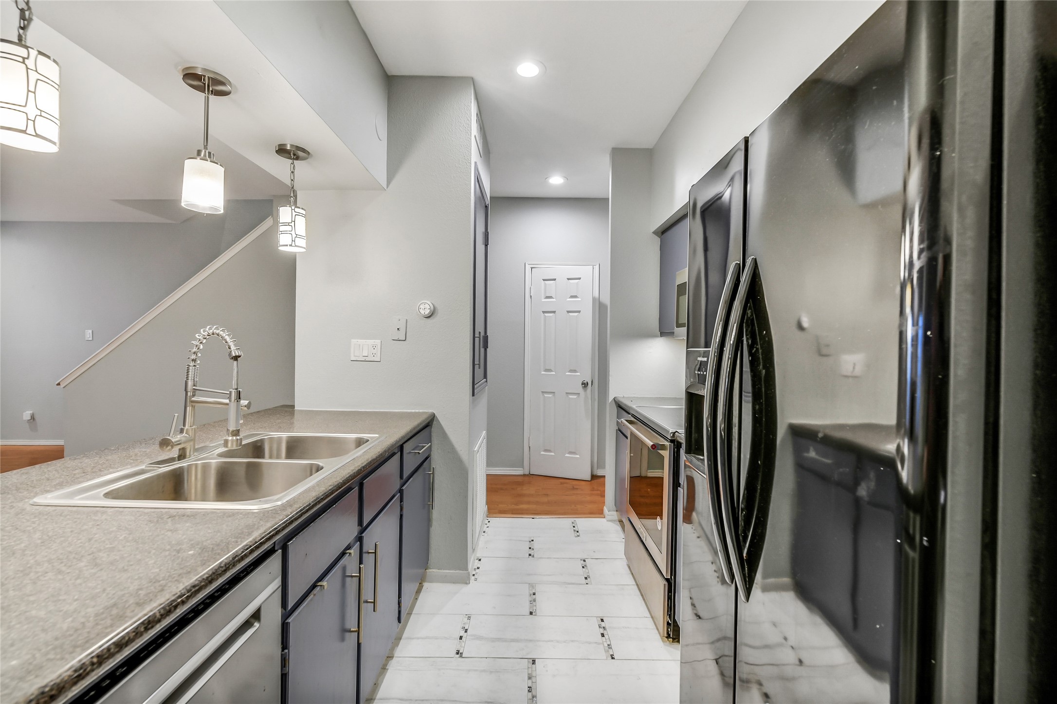 4001 Tanglewilde Street, Unit 1402 Houston, TX 77063 - Photo 10 of 23 This inviting galley-style kitchen features updated tile flooring and sleek stainless steel appliances, with a convenient guest half bath just across the entrance.