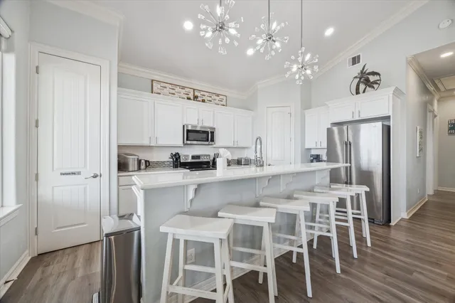 a kitchen with stainless steel appliances a table chairs refrigerator and microwave