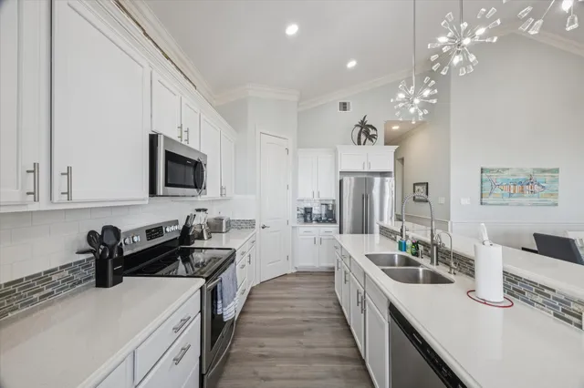 a kitchen with stainless steel appliances a sink dishwasher a stove top oven a refrigerator with island and cabinets