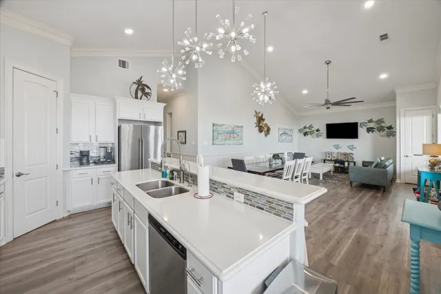 a large white kitchen with a stove a chandelier a dining table and chairs